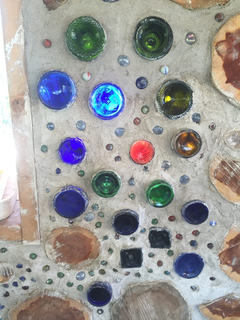 Using bottles in a cordwood wall is a beautiful way to reuse common materials while letting in light and color! #cordwood #bottlewall