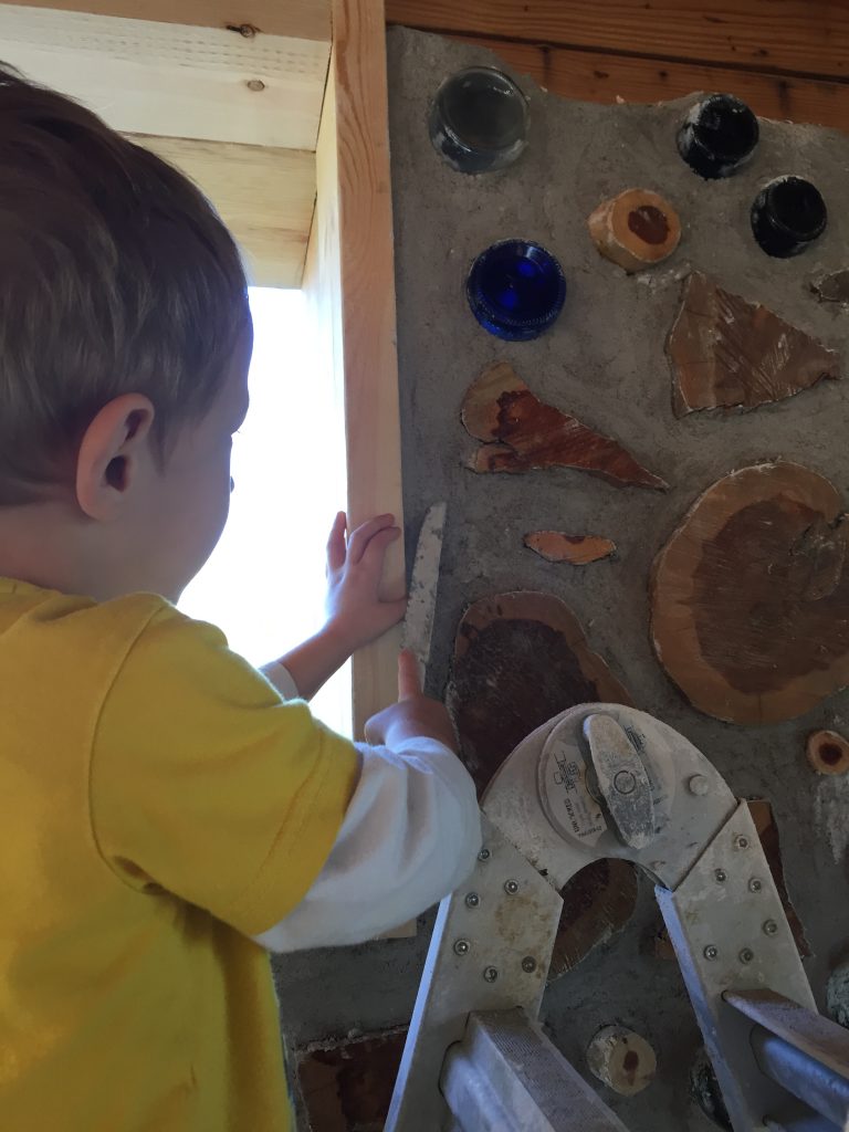Even our 3-year-old son can help with the cordwood! Here he is smoothing the wall after the adults spent the day building.