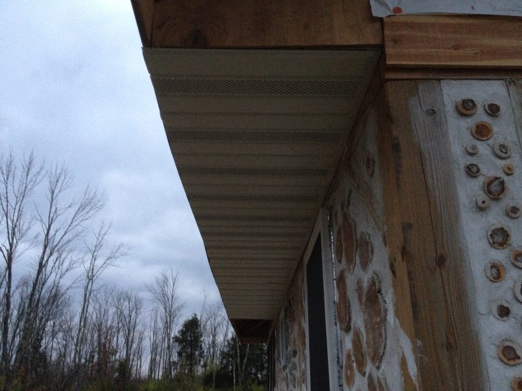 Soffit installation in progress on a cordwood house