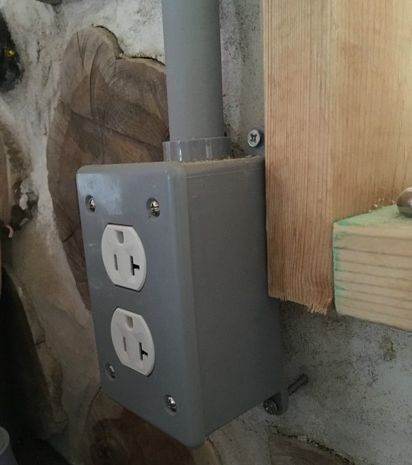 Example of a surface mounted outlet on a cordwood wall. Here's what you need to know when running electrical in or on cordwood masonry.